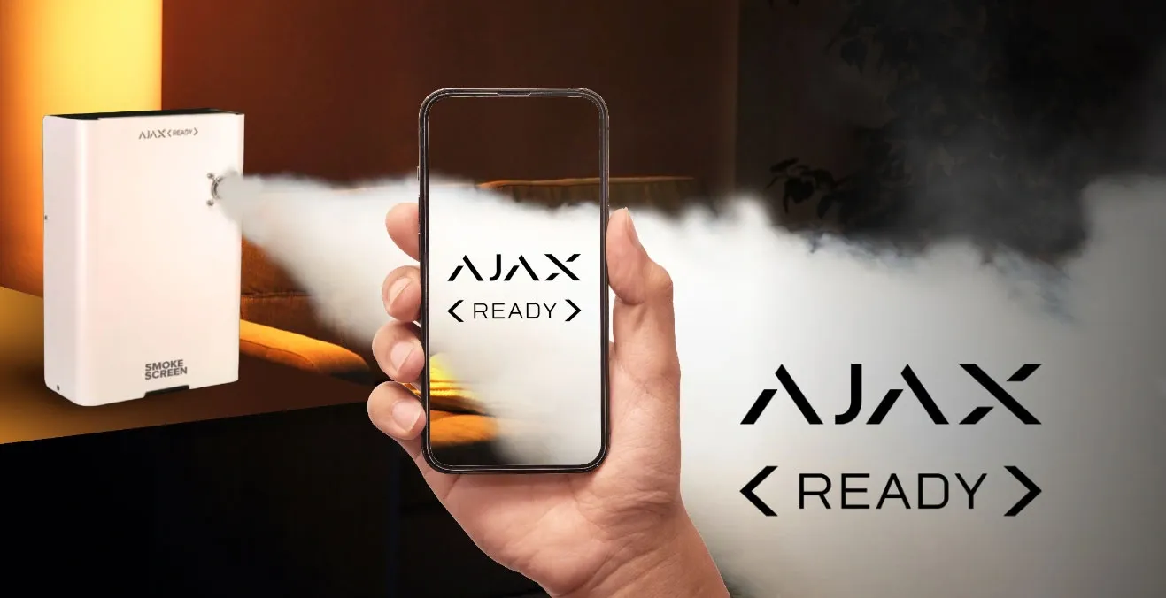Un generatore nebbiogeno Concept marcato Ajax Ready eroga nebbia, accanto a un telefono che mostra la schermata Ajax Ready.